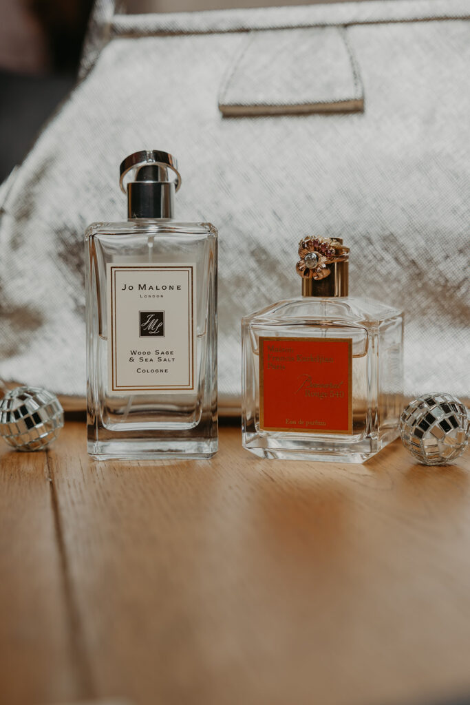 Perfume and cologne with wedding rings placed on top of the bottles
