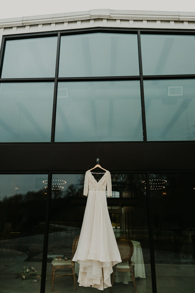 Wedding dress hanging in front of large window wall