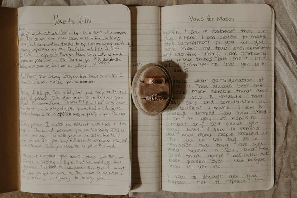 Handwritten wedding vows with rings in the center of the vow books