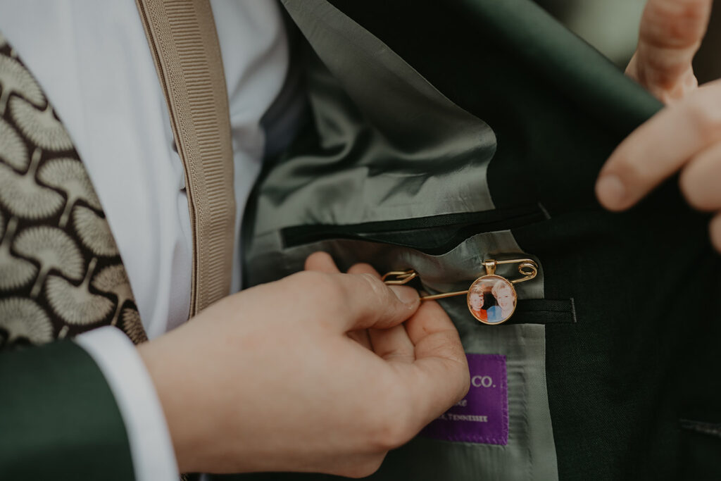 Fastening a pin inside a suit jacket, the pin has a photo on it.