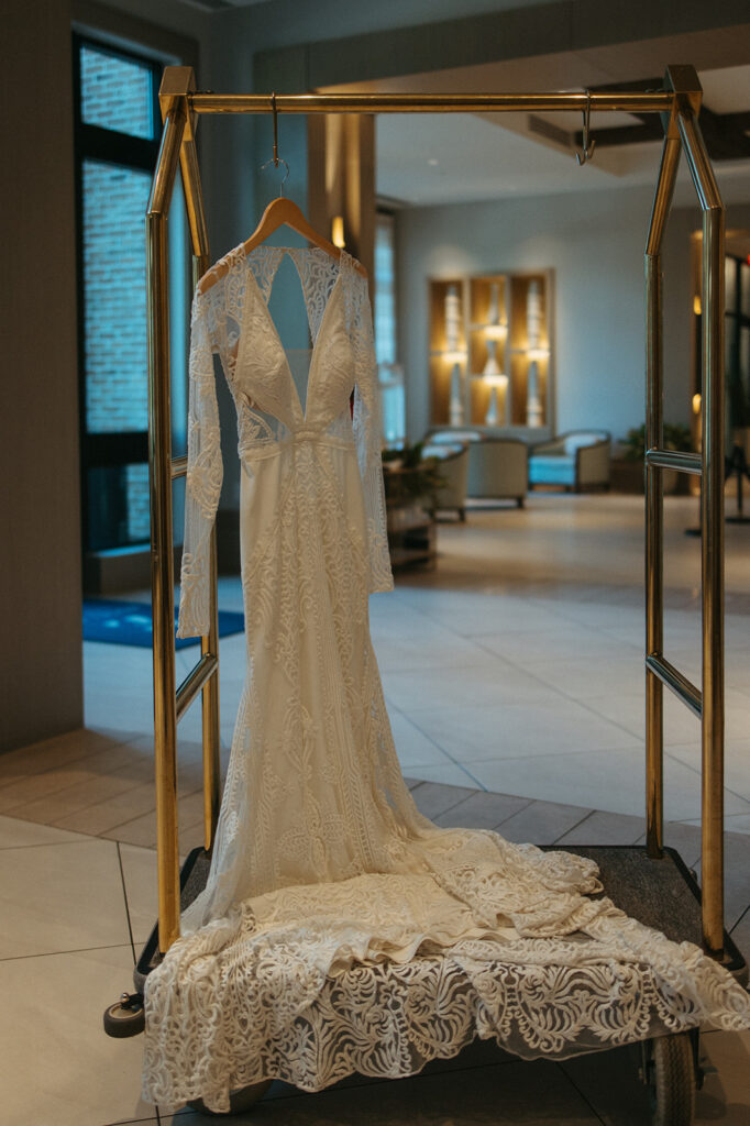 LVD Bridal gown hangs on luggage cart in hotel lobby at Miramar Beach
