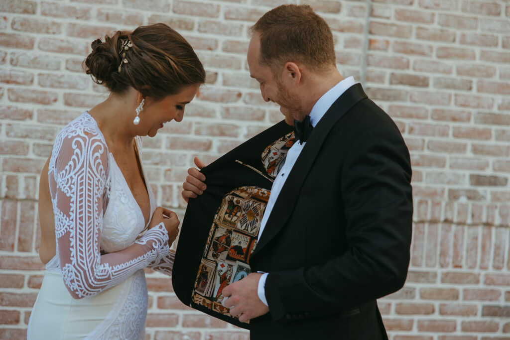 Bride looks at inside lining of groom's custom Richards Bespoke suit in Miramar Beach destination wedding