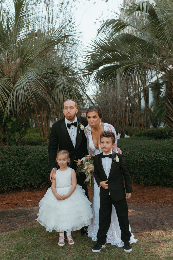 Bride, groom, ring bearer, and flower girl make funny faces at the camera