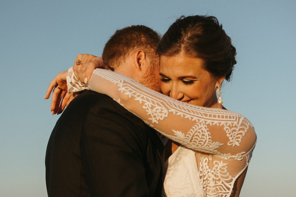 Bride smiles as groom kisses her neck in Miramar Beach wedding