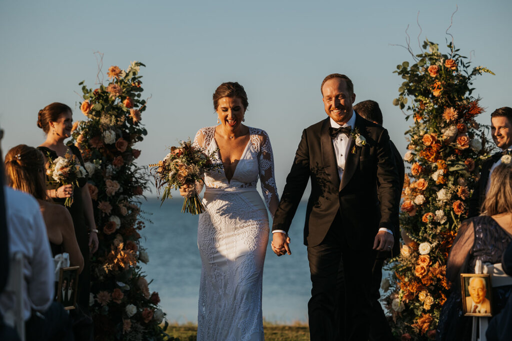 Bride and groom smile as they make their golden hour grand exit at Miramar Beach