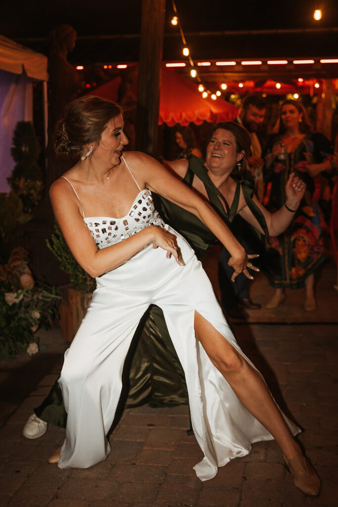 Bride and wedding guest bust a move on the dance floor of Louis Louis