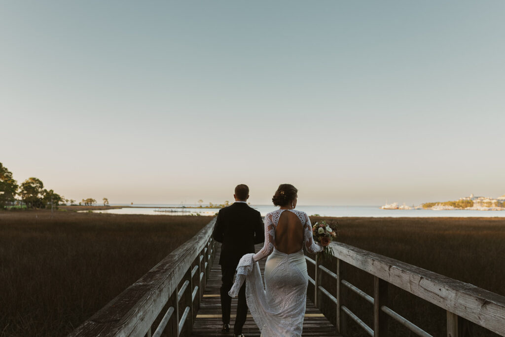 Bride and groom walk down 30A boardwalk towards Miramar Beach