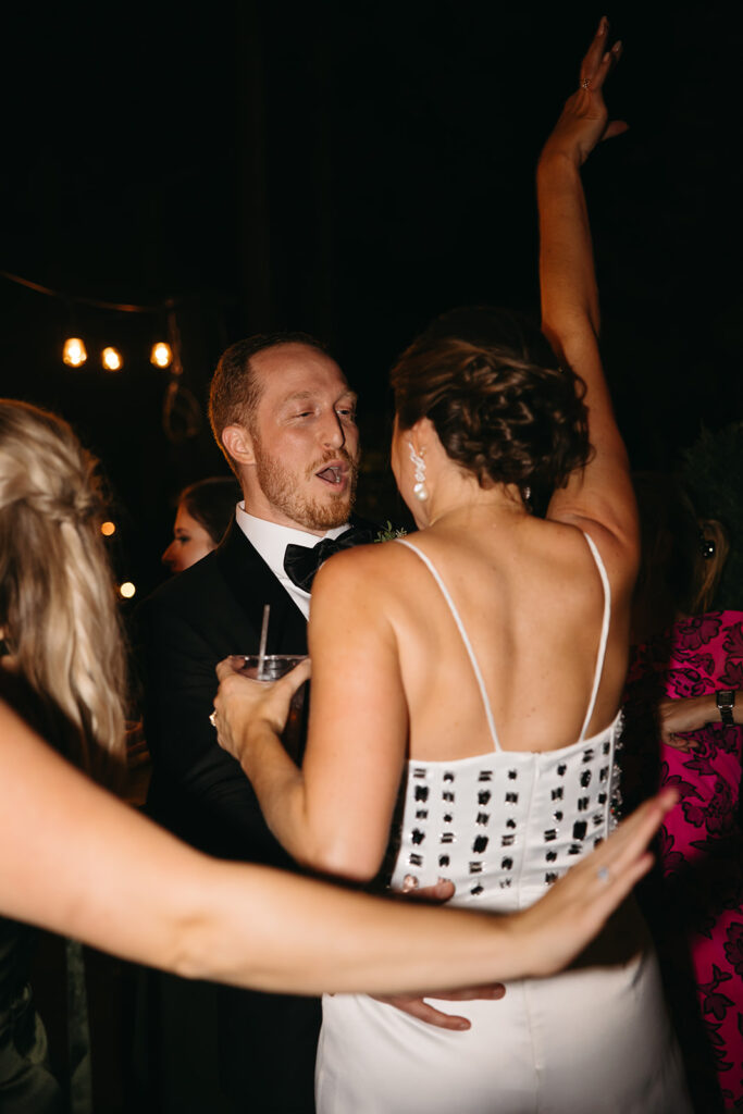 Groom looks adoringly at bride while she dances at wedding reception