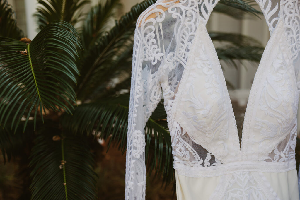 Bridal gown hangs in front of lush majesty palms on Miramar Beach 