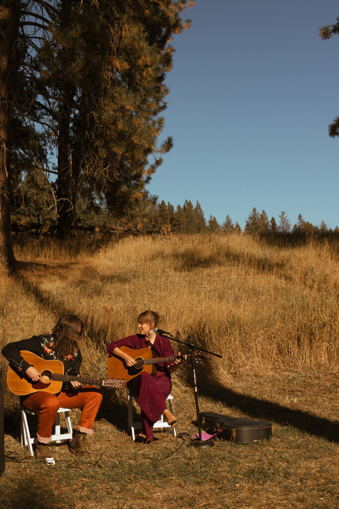 Wedding musicians prepare for bride to come down the aisle as they sit among prairie grass at Settlers Creek wedding venue in Coeur d'Alene, Idaho