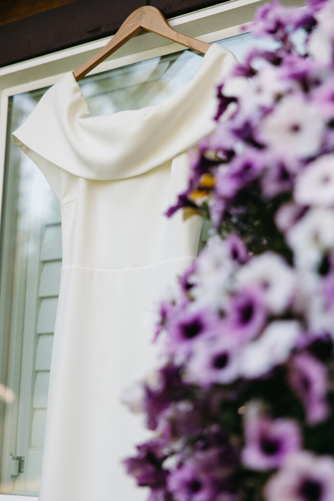 Satin wedding gown hangs near purple petunias