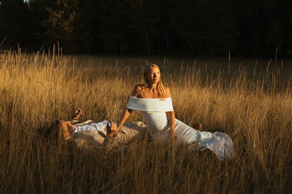 Bride and groom lay in prairie grass in stunning Idaho destination wedding golden hour