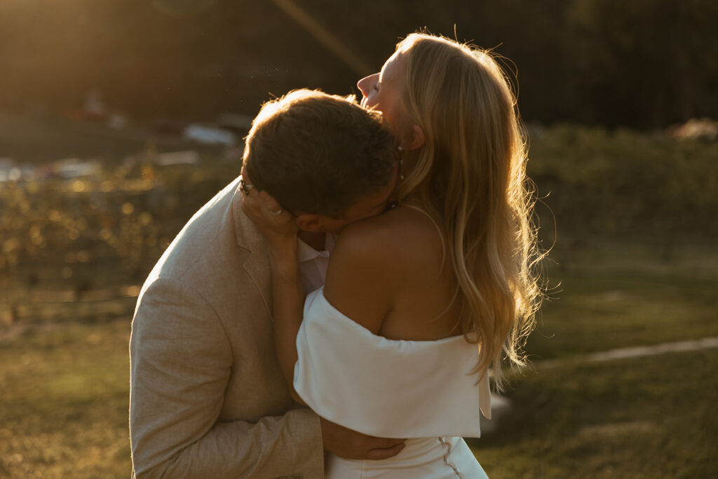Groom kisses bride's neck as the sunlight cascades over them in Coeur d'Alene wedding.