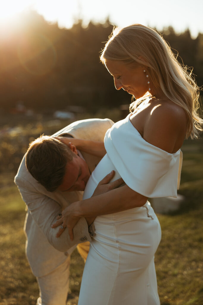Groom kisses expecting bride's stomach in stunning golden hour portrait