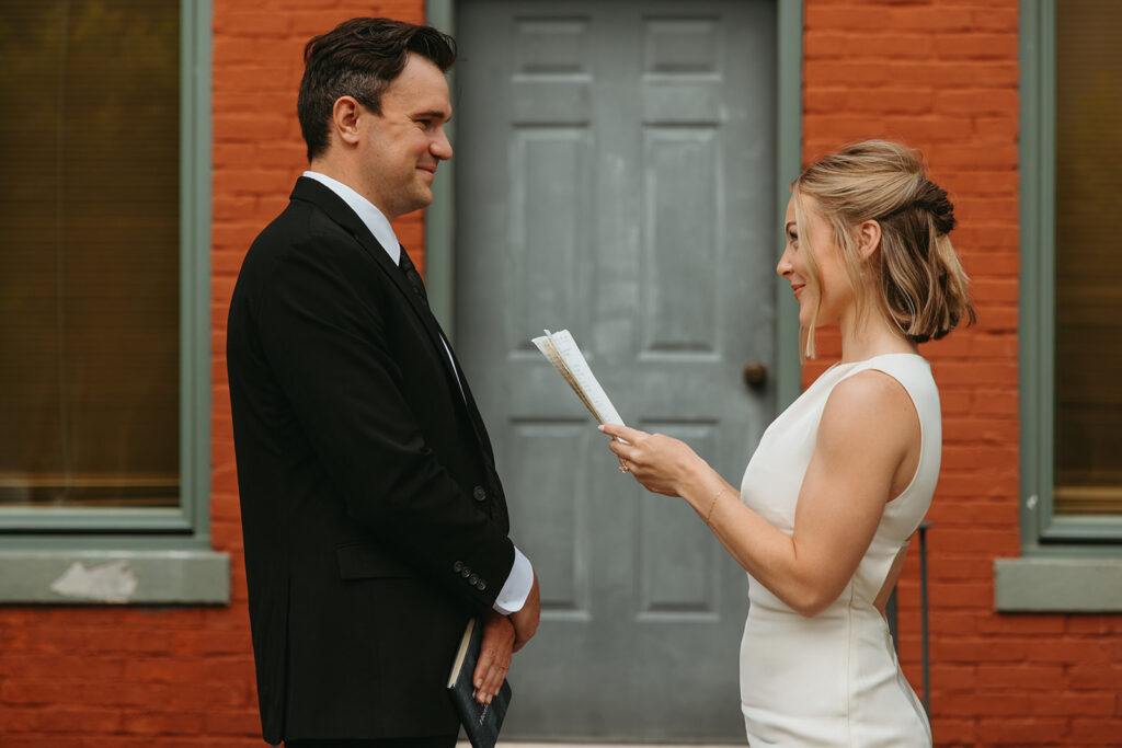 Bride grins at groom as she reads her vows