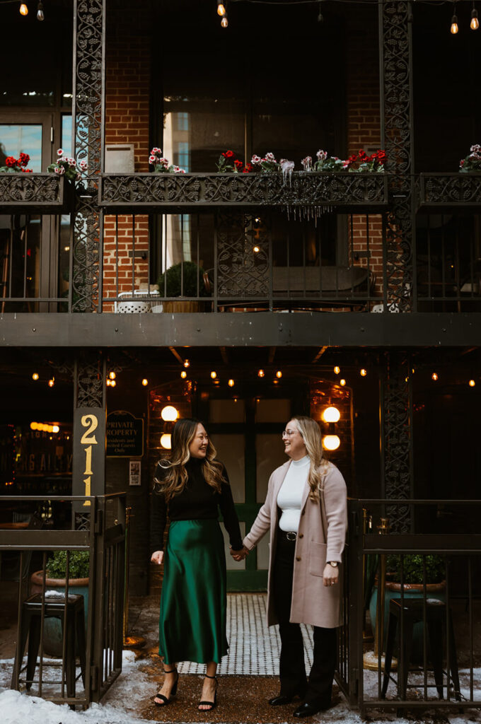 Couple holds hands outside Printer's Alley balcony in downtown Nashville. 