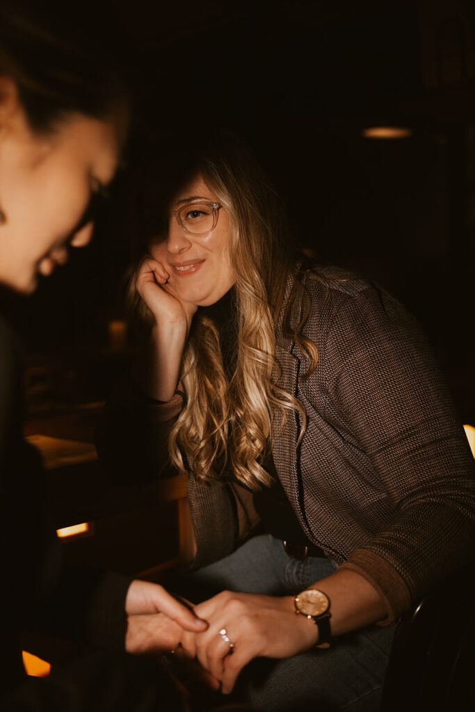 Woman looks at her fiance adoringly in romantic cocktail bar atmosphere.