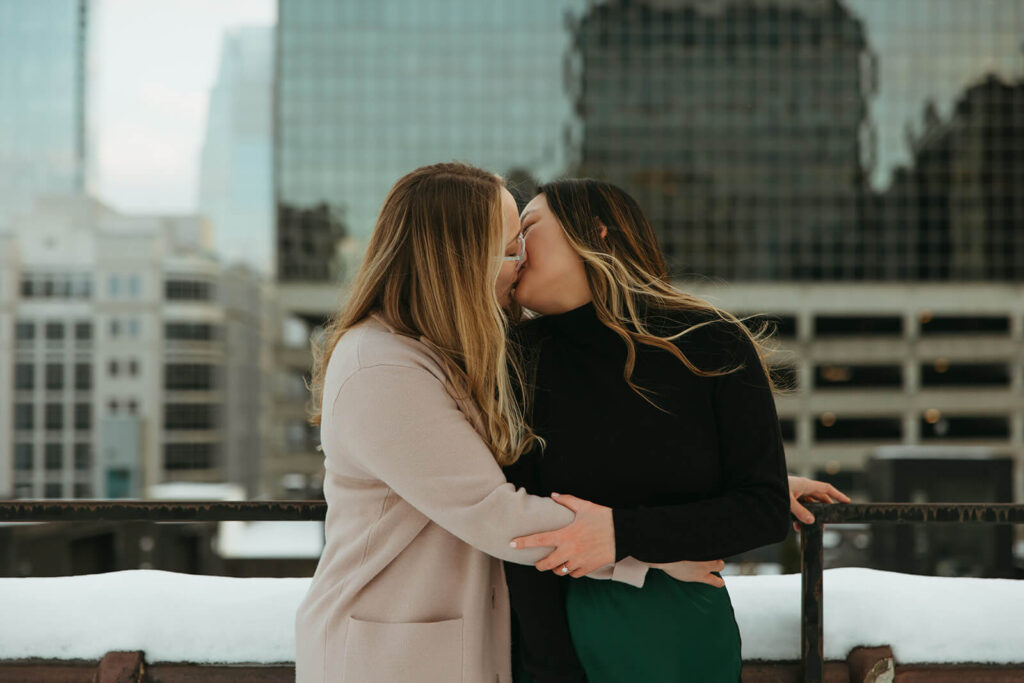 Couple embraces in romantic kiss with Nashville skyline behind them