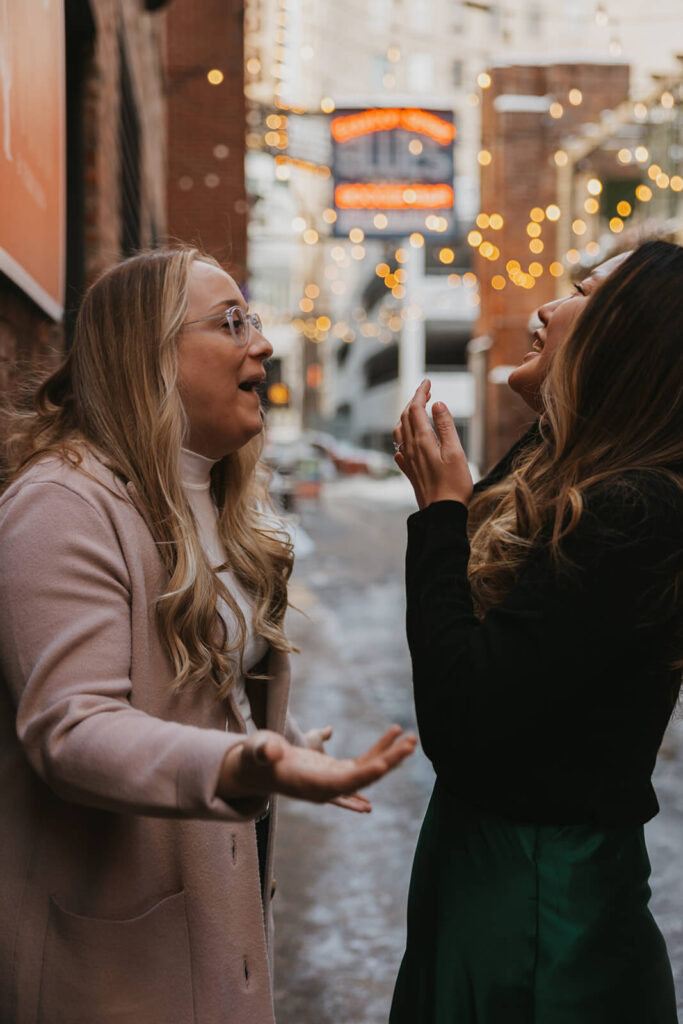 Couple laughs as they stand in Printer's Alley during mini-moon engagement session by Nashville luxury wedding photographer.