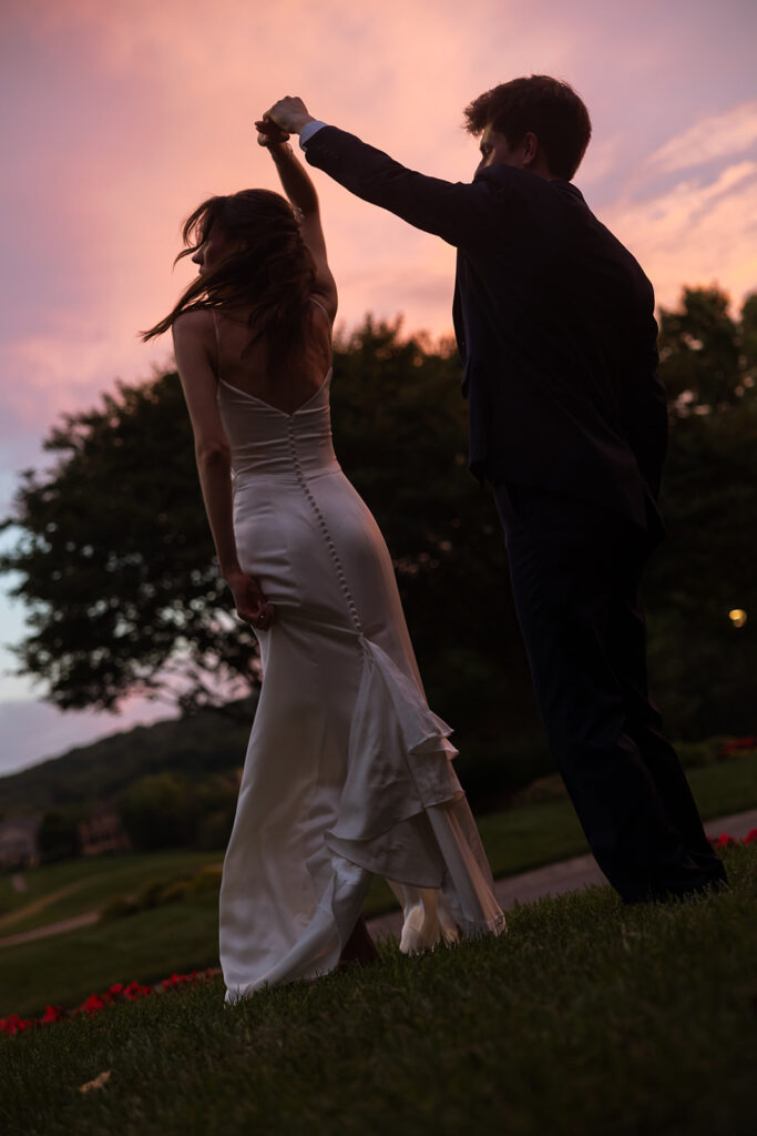 Groom twirls his bride during couples portraits at sunset