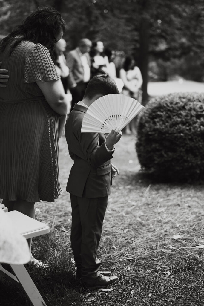 Ring bearer fans himself during humid documentary style wedding