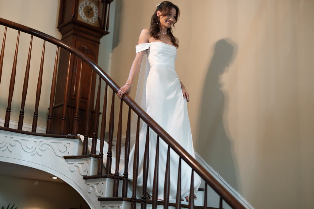 Bride smiles at her father as she comes down the stairwell in her gown