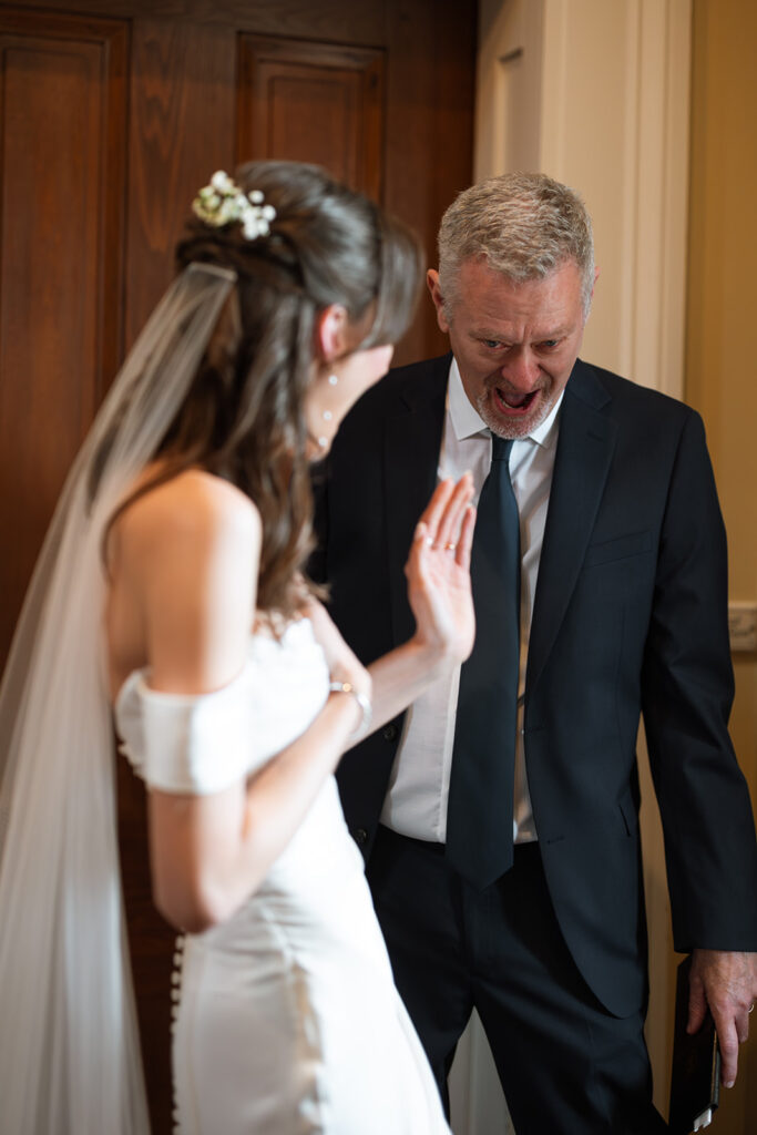 Father looks on at his daughter in disbelief during first look in documentary style wedding photos