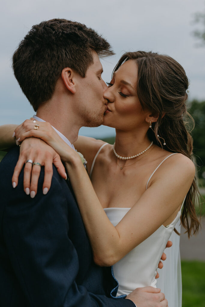 Bride and groom kiss in documentary style wedding photos at dusk