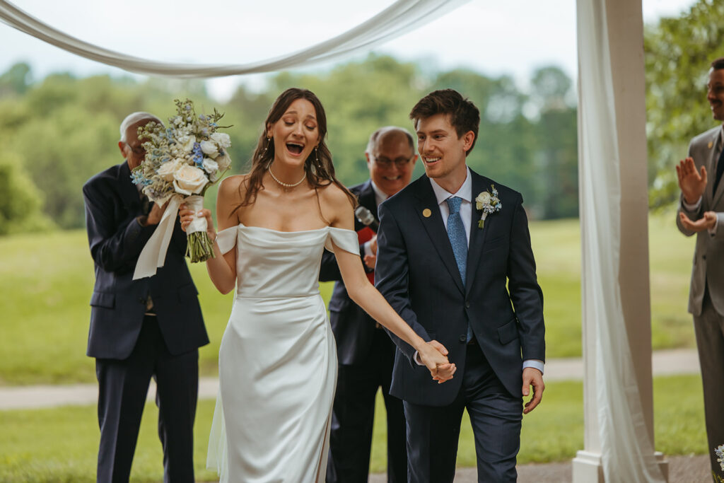 Bride smiles and cries simultaneously as she comes down the aisle after saying her vows