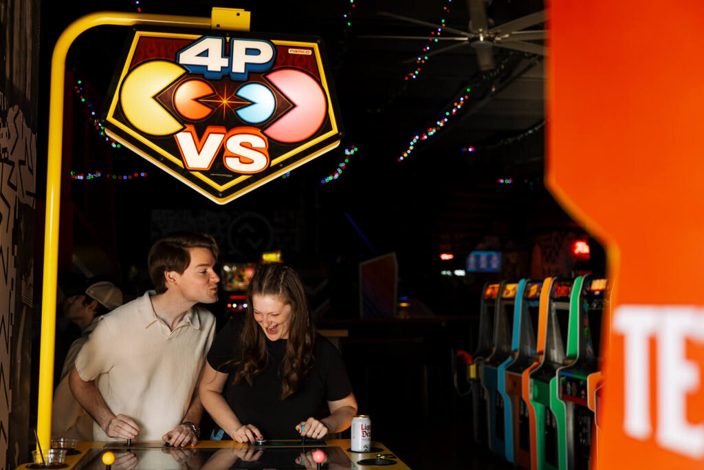 Man goes to kiss his fiancee as the plays PacMan at Nashville arcade bar