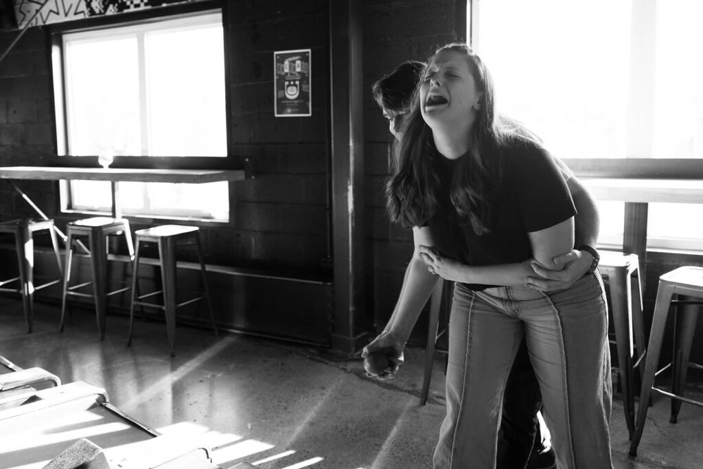 Man hugs woman from behind as they play skeeball