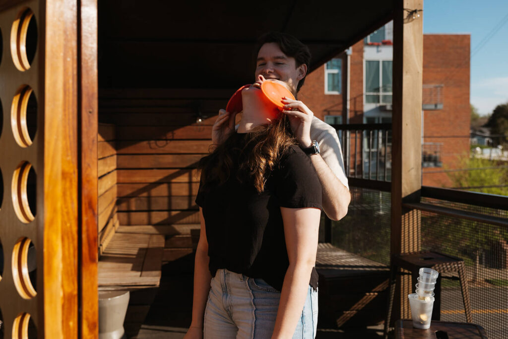 Man covers woman's eyes with jumbo Connect Four tiles