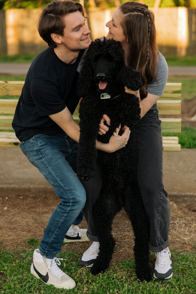 Man, woman, and poodle gather in a cute hug