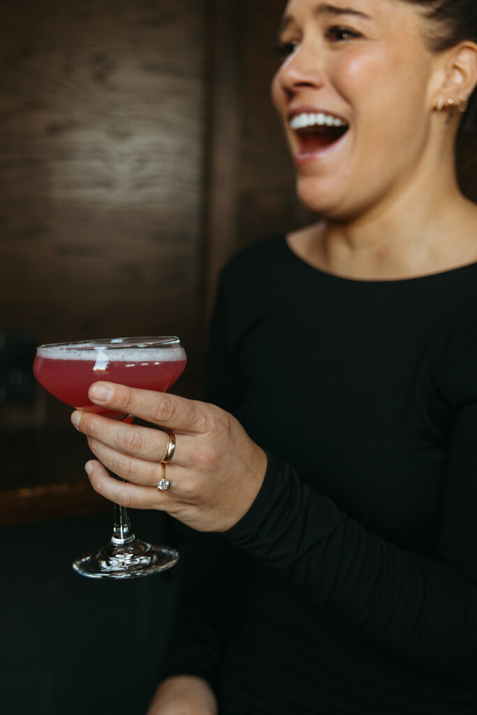 Woman laughs as she nearly spills her cocktail