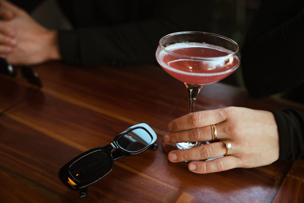 Cocktail and sunglasses sit on booth at Never Never in Nashville 