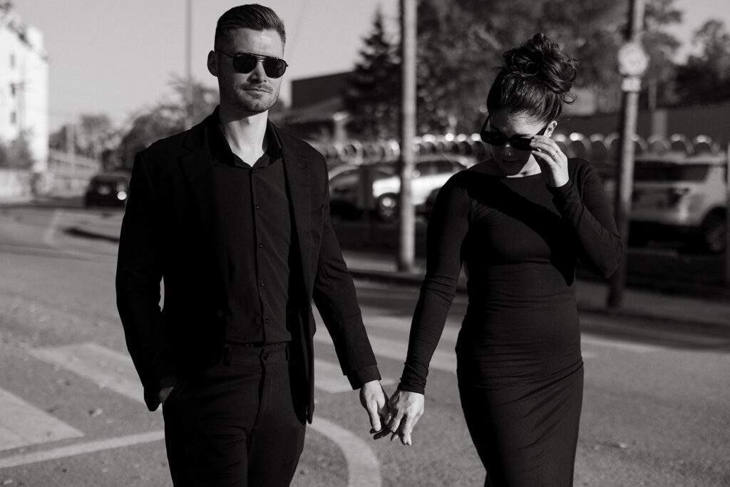 Man and woman walk hand in hand down the street wearing all black