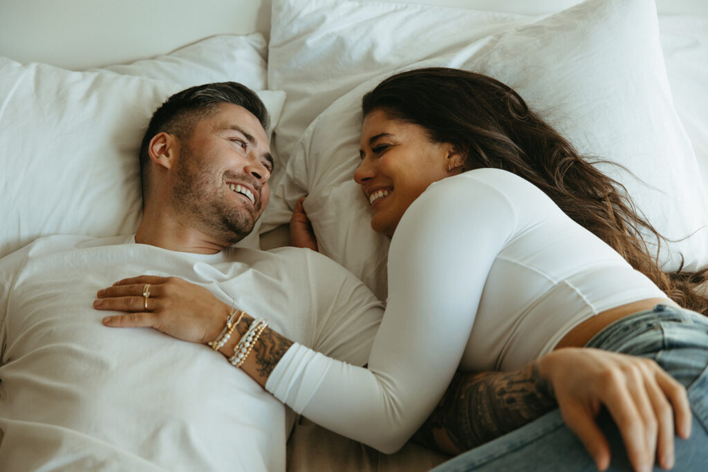 Engaged couple chats while laying in bed together