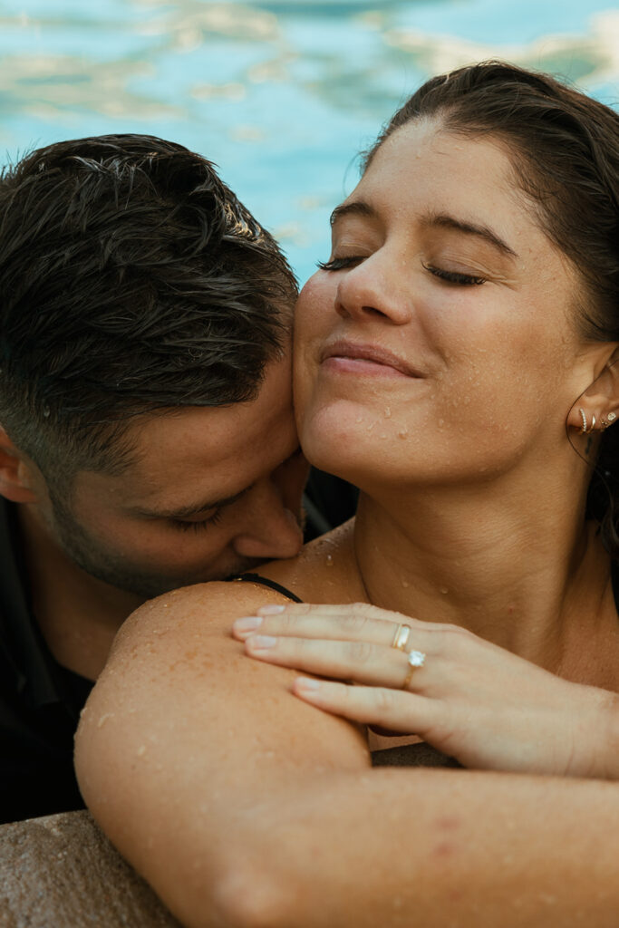 Man kisses woman's shoulder for engagement photo poses