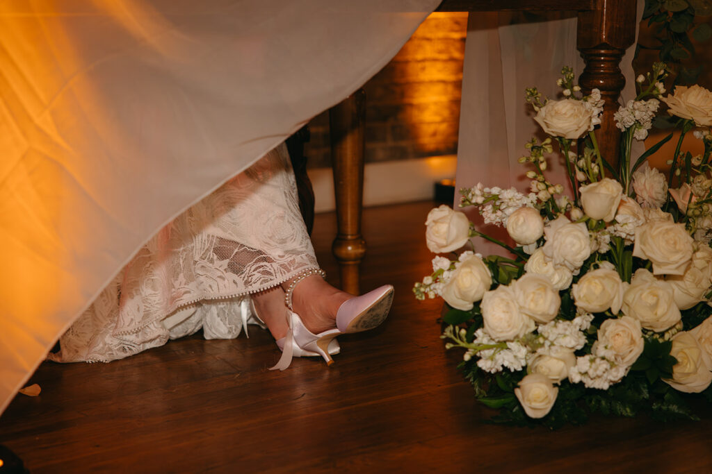 Bride's feet rest near the florals at the head table at wedding venue in Tennessee