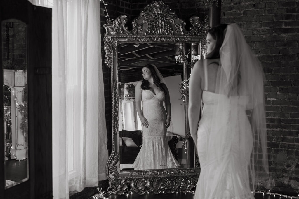 Bride looks over her shoulder at her reflection in the mirror