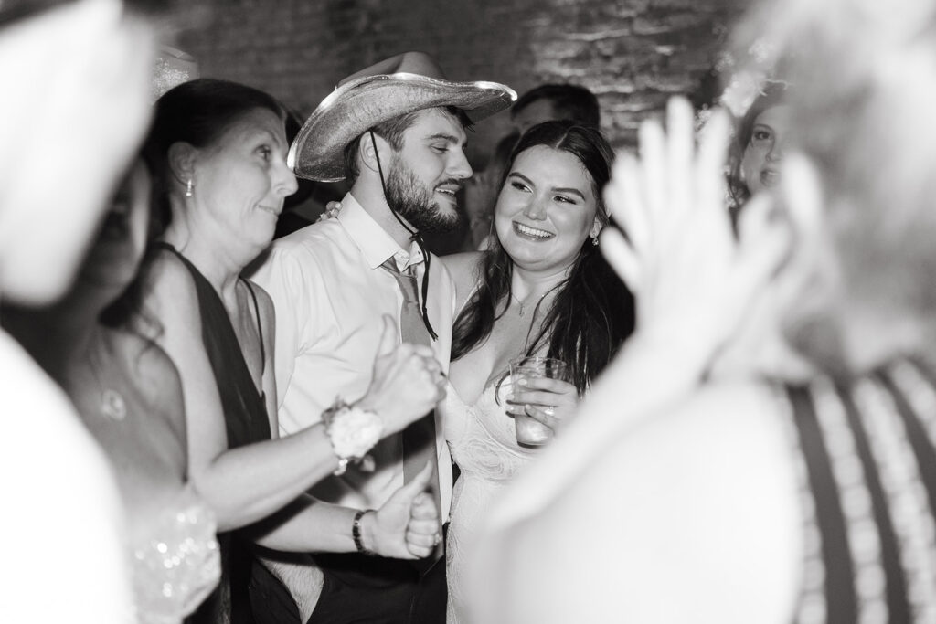 Groom smiles at his bride while they converse with wedding guests