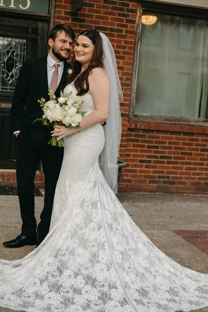 Groom smiles at bride as they stand on the Gallatin main street outside Emerald Union wedding venue in Tennessee