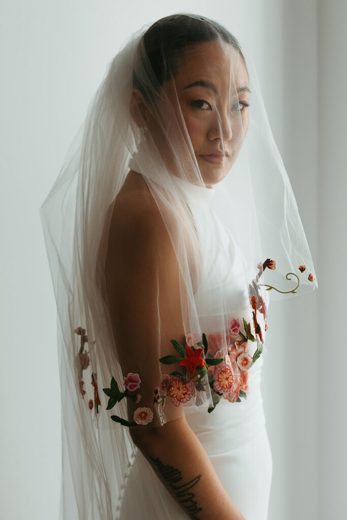 Elegant bride looks at the camera under the cover of her veil