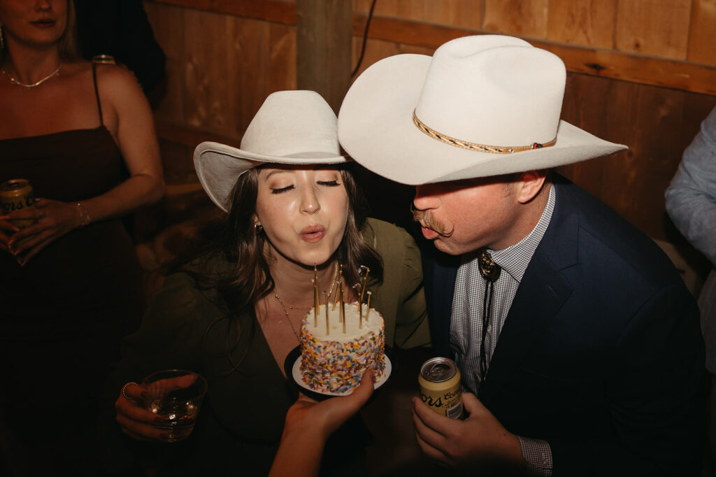 Wedding guests blow out candles on mini cake