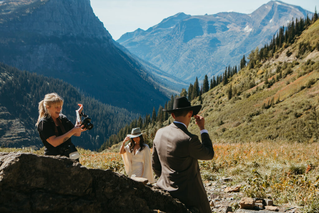 Photographer laughs with bride and groom as they capture their Yellowstone wedding in Glacier National Park in Montana.