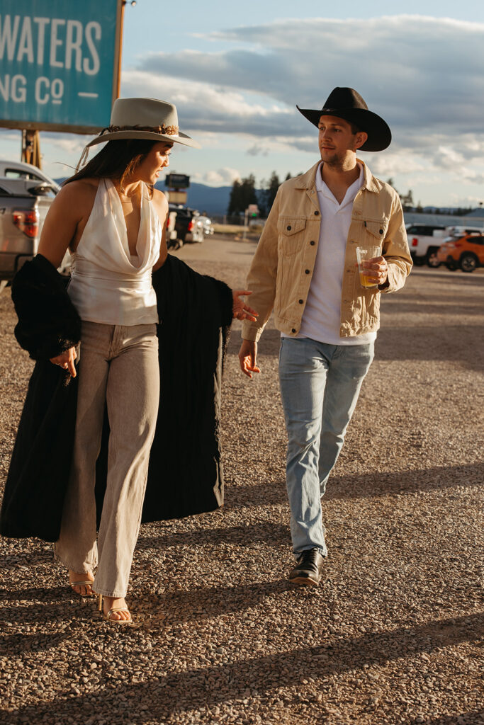 Newlyweds walk hand in hand through parking lot of Sacred Waters Brewing Co. in Montana. 