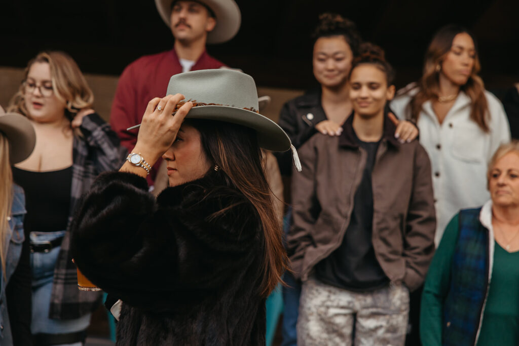 Bride-to-be fixes her cowboy hat as friends look on.