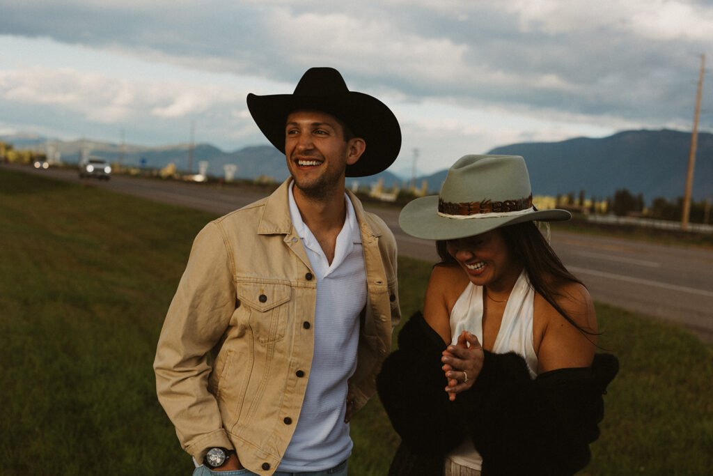 Couple laughs as they stand alongside highway in Montana.