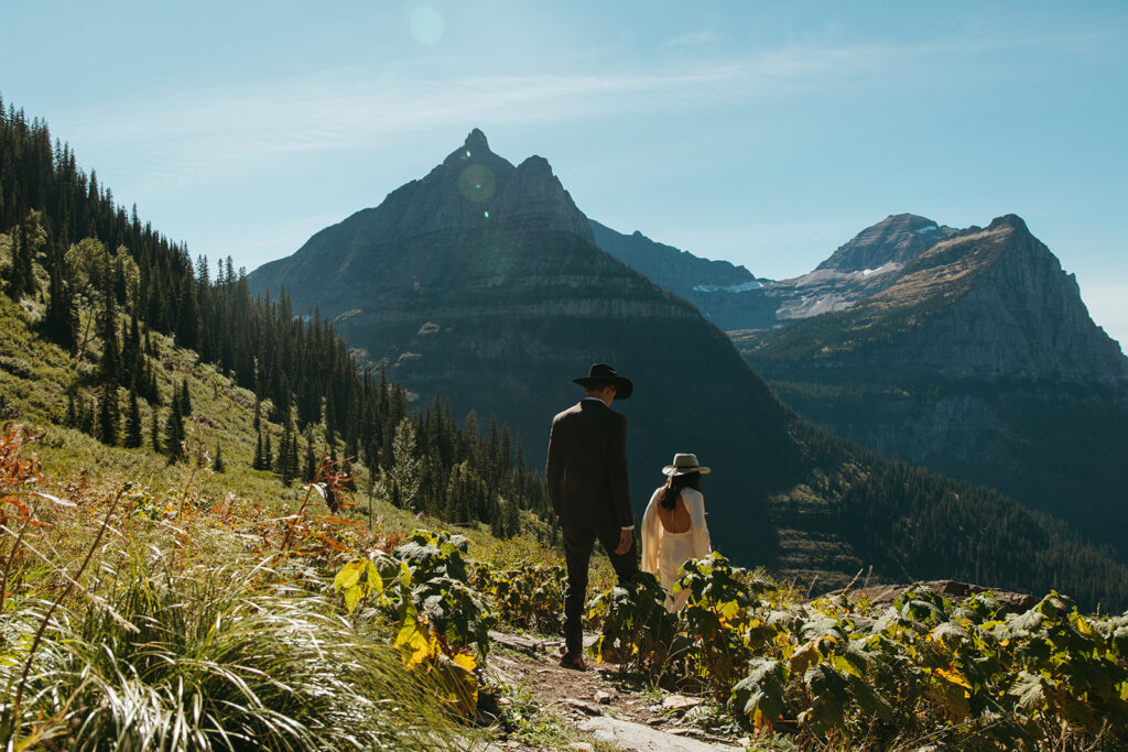 Bride and groom walk through Glacier National Park for Yellowstone wedding in Montana.