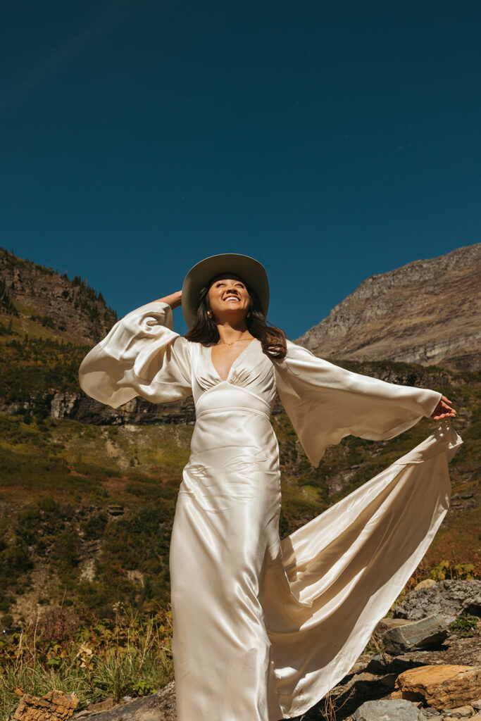 Cowgirl bride stretches her arms towards the sun with a smile on her face.